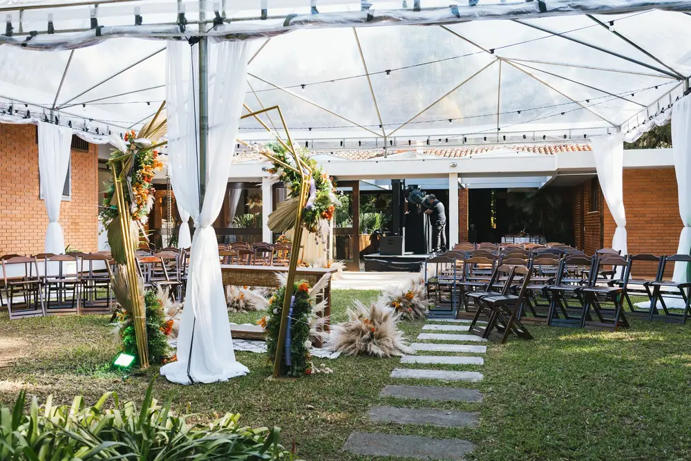 Cerimônia ao ar livre montada com arco floral e cadeiras no jardim